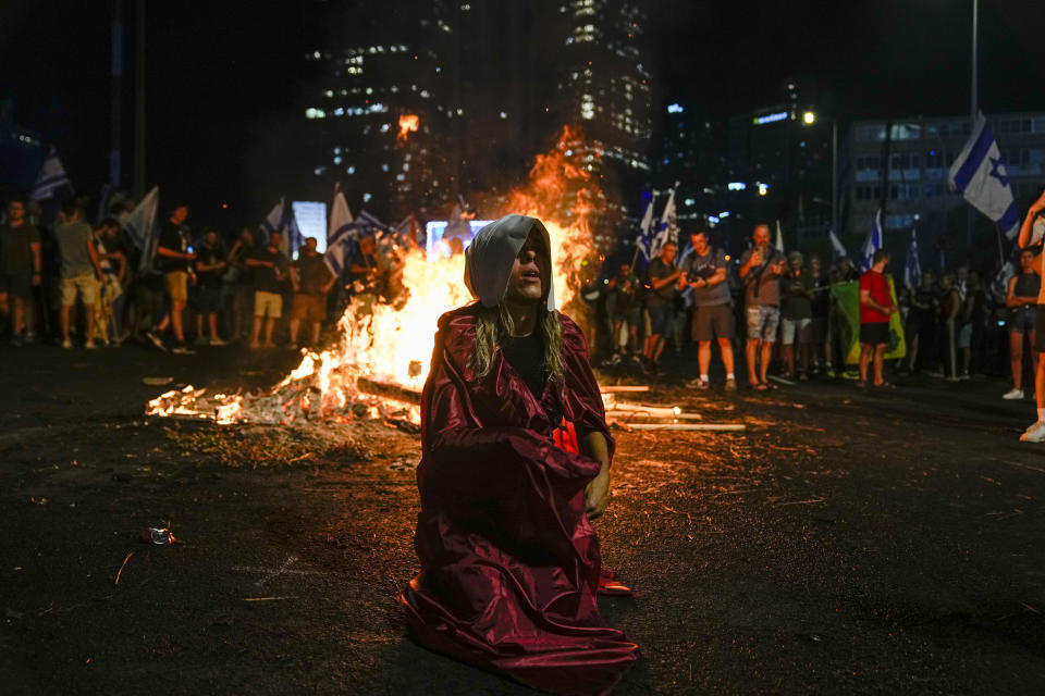 A protester dressed as a character from "The Handmaid's Tale" TV series blocks a freeway during a protest against plans by Prime Minister Benjamin Netanyahu's government to overhaul the judicial system in Tel Aviv, Israel, Wednesday, July 5, 2023. (AP Photo/Ohad Zwigenberg)