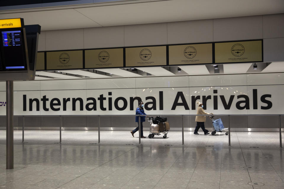 FILE - In this Tuesday, Jan. 26, 2021 file photo, arriving passengers walk past a sign in the arrivals area at Heathrow Airport in London, during England's third national lockdown since the coronavirus outbreak began. The British government is gearing up to ban international arrivals from four more countries — Bangladesh, Kenya, Pakistan and the Philippines — amid concerns over new virus variants but opted against including France and other European nations facing a resurgence of the virus. The Department for Transport said Friday April 2, 2021 that the number of countries on its “red list” will reach 39 when the latest restrictions take effect in England beginning April 9. (AP Photo/Matt Dunham, File)