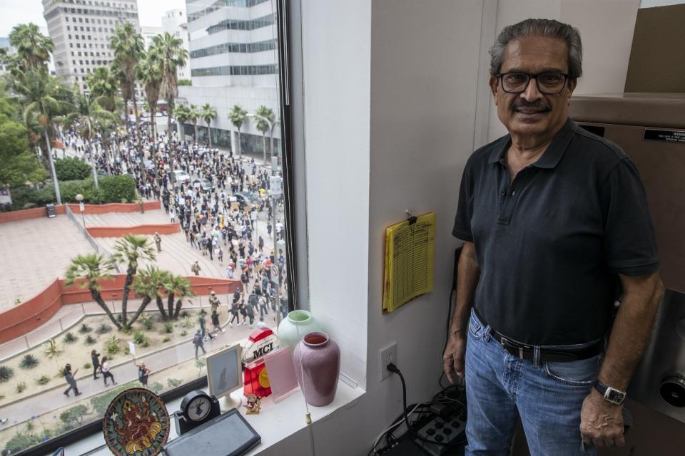 Sanat Shah, owner of Shah Jewel Inc., looks out over Pershing Square where hundreds of protesters march.