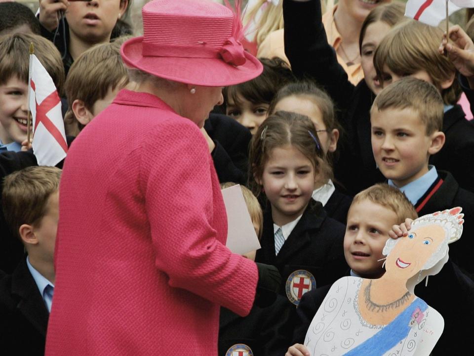 Queen Elizabeth accepts a card from a fan.