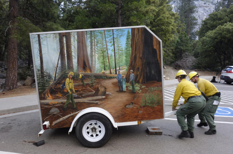 In this June 10, 2019 photo, fire information officers Rebecca Paterson, left, and Mike Theune, right, move a trailer containing firefighting equipment and other items they use to educate visitors about a prescribed burn in Kings Canyon National Park, Calif. The prescribed burn, a low-intensity, closely managed fire, was intended to clear out undergrowth and protect the heart of Kings Canyon National Park from a future threatening wildfire. The tactic is considered one of the best ways to prevent the kind of catastrophic destruction that has become common, but its use falls woefully short of goals in the West. (AP Photo/Brian Melley)