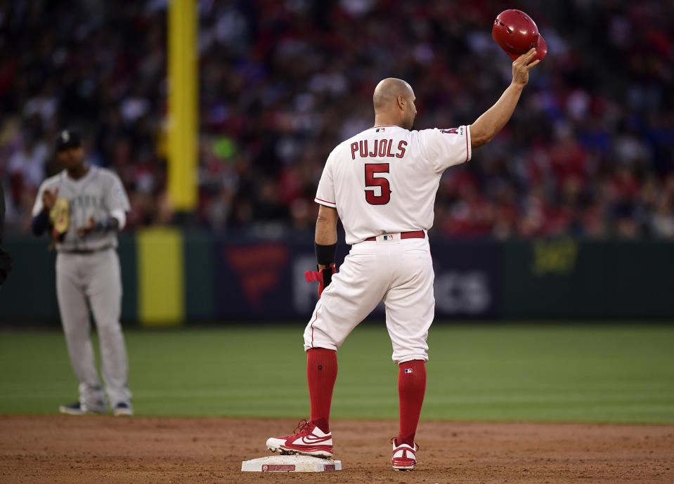 Los Angeles Angels' Albert Pujols, right, tips his helmet to fans after hitting an RBI double as Seattle Mariners shortstop Tim Beckham claps during the third inning of a baseball game Saturday, April 20, 2019, in Anaheim, Calif. With that RBI, Pujols tied Babe Ruth for 5th place on the all-time RBI list with 1,992. (AP Photo/Mark J. Terrill)