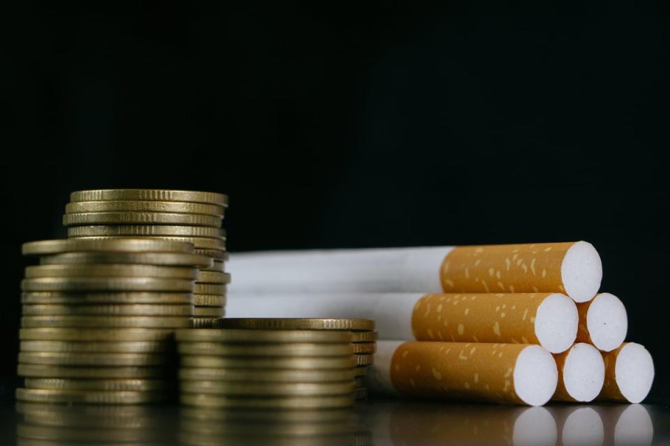 A pile of coins next to a bunch of cigarettes.