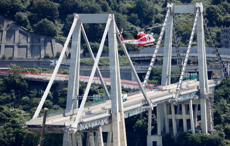 FILE PHOTO: Firefighter helicopter flies over the collapsed Morandi Bridge in the port city of Genoa