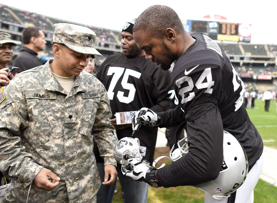 OAKLAND, CA - DECEMBER 07:  Charles Woodson #24 of the Oakland Raiders signs an autograph for a member of the U.S. Army prior to playing the San Francisco 49ers at O.co Coliseum on December 7, 2014 in Oakland, California.  (Photo by Thearon W. Henderson/Getty Images)