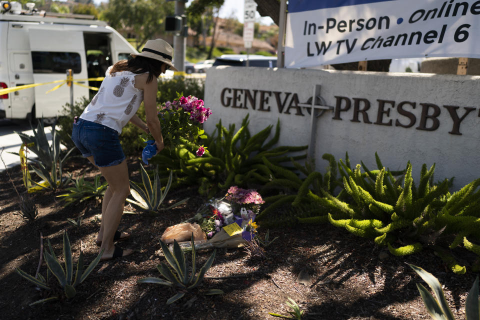 FILE - Joanna Garcia, 47, leaves flowers outside Geneva Presbyterian Church to honor victims in Sunday's shooting at the church in Laguna Woods, Calif., Monday, May 16, 2022. After a weekend of gun violence in America, when shootings killed and wounded people grocery shopping, going to church and simply living their lives, the nation marked a milestone of 1 million deaths from COVID-19. The number, once unthinkable, is now a pedestrian reality in the United States, just as is the reality of the continuing epidemic of gun violence that kills tens of thousands of people a year. (AP Photo/Jae C. Hong, File)