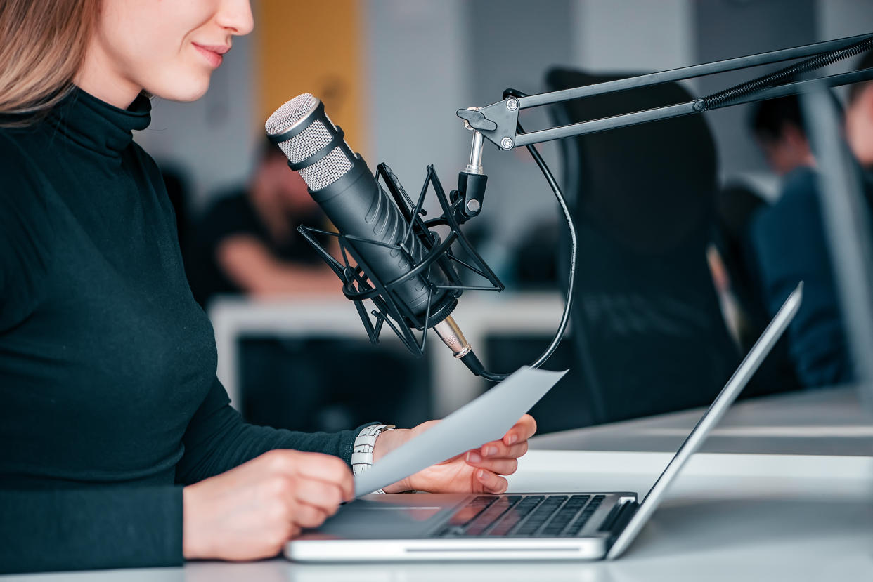 Young woman recording a podcast in a studio, close-up.