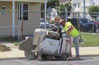 A worker uses an industrial cutting machine to open a section of the street in Ocean City, N.J. on Sept. 12, 2023, at the start of land-based probing along the right-of-way where a power cable for New Jersey's first offshore wind farm is proposed to run. Several protestors were arrested trying to block the work for the project being done by Danish wind energy company Orsted. (AP Photo/Wayne Parry)