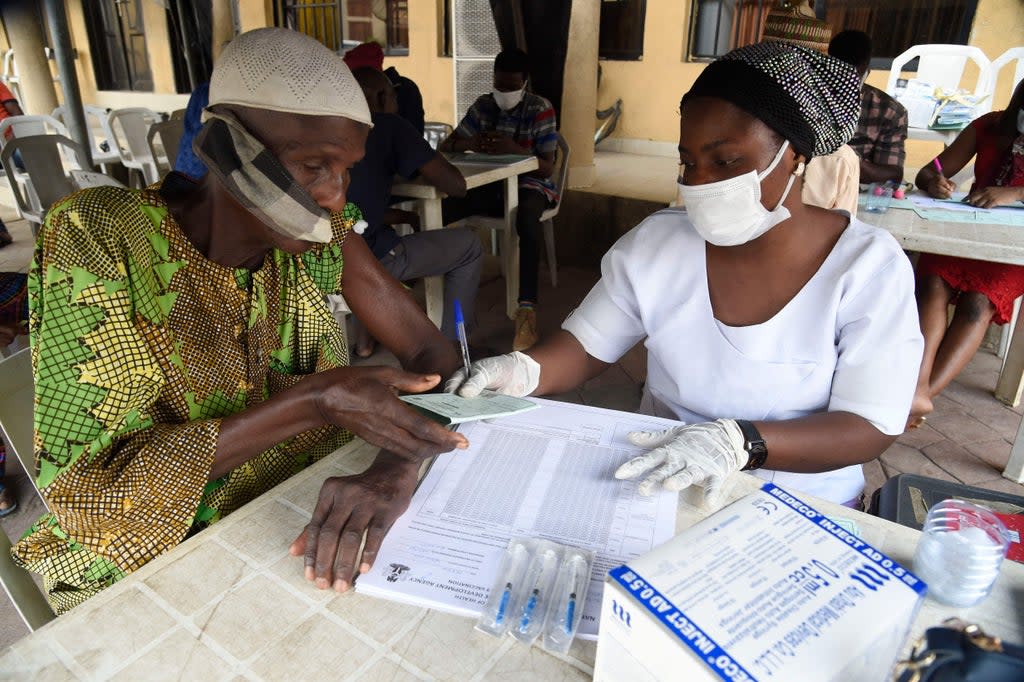 Un hombre recibe una tarjeta de vacunación de un funcionario de salud en Lagos, Nigeria (AFP via Getty Images)