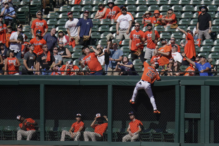 Baltimore Orioles right fielder Anthony Santander climbs the wall while trying to catch a home run by Cleveland Guardians' Jose Ramirez during the first inning of a baseball game, Saturday, June 4, 2022, in Baltimore. (AP Photo/Julio Cortez)