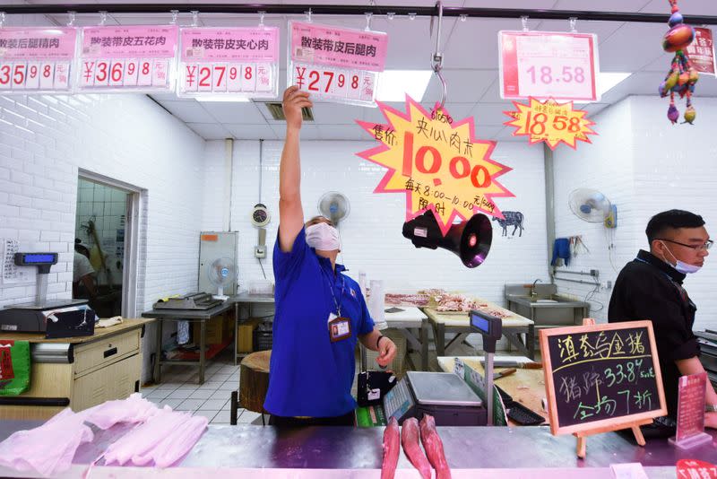 Staff member puts up a price sign at a pork counter inside a supermarket in Hangzhou