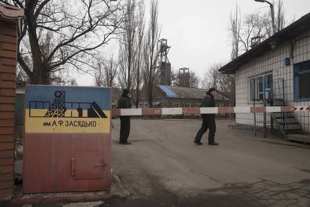 Men stand at the gate to Zasyadko coal mine in Donetsk March 4, 2015. REUTERS/Baz Ratner