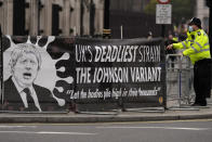 FILE - A police officer stands beside a protest banner at Parliament Square in London, Wednesday, Nov. 24, 2021. The coronavirus's omicron variant kept a jittery world off-kilter Wednesday Dec. 1, 2021, as reports of infections linked to the mutant strain cropped up in more parts of the globe, and one official said that the wait for more information on its dangers felt like “an eternity.” (AP Photo/Frank Augstein, File)