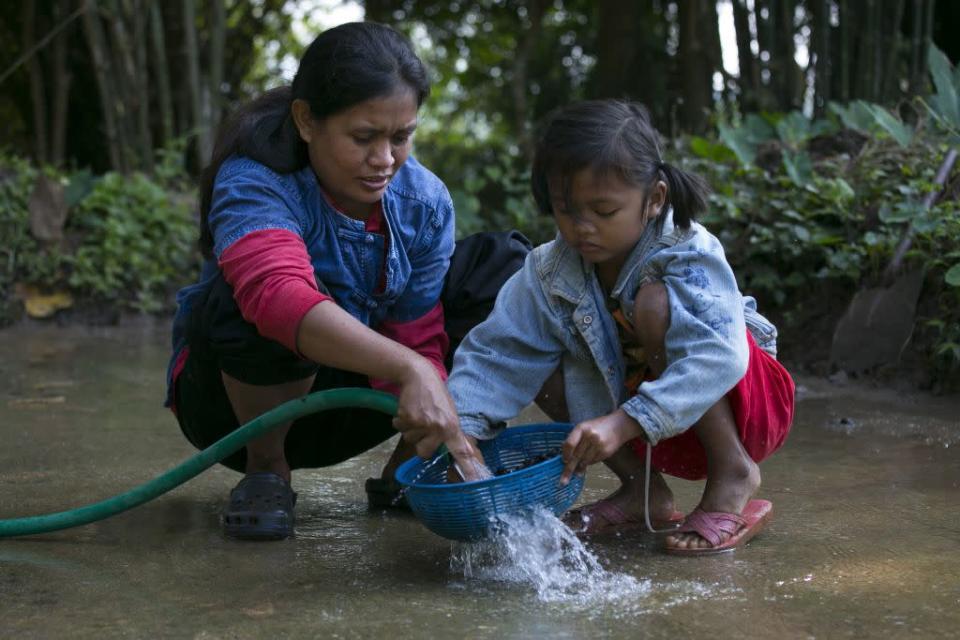 Niang, a mahout's wife, and her daughter Ari, 6, wash coffee beans after picking them from the dung at an elephant camp at the Anantara Golden Triangle resort in Golden Triangle, northern Thailand.