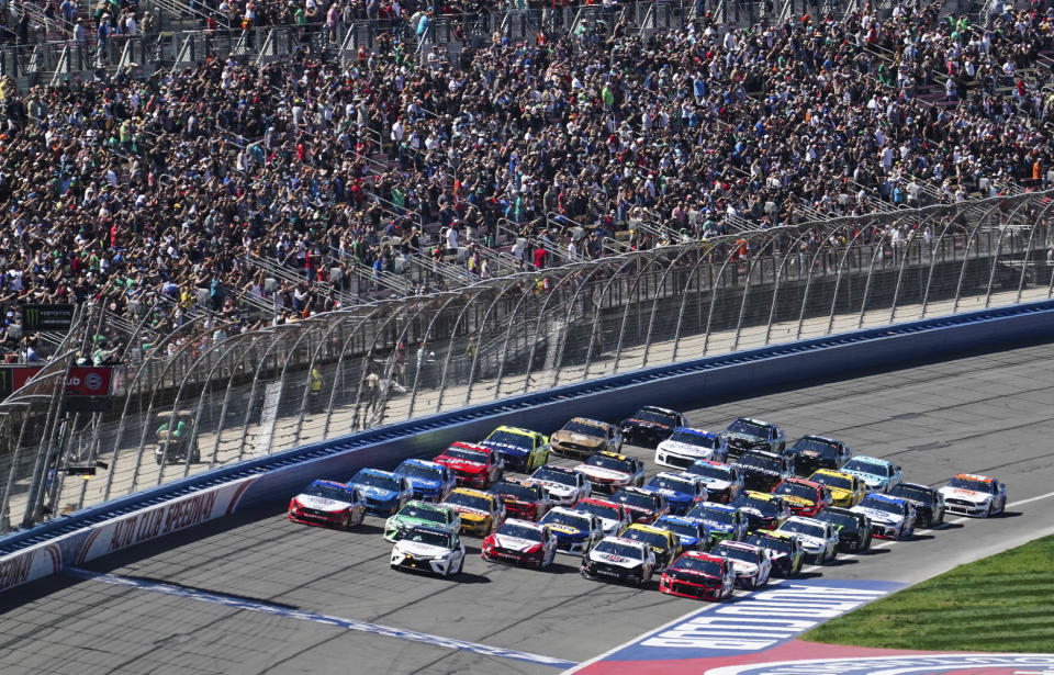 NASCAR Cup Series cars line up five wide in a salute to fans during pace laps for the NASCAR Cup Series auto race at Auto Club Speedway, in Fontana, Calif., Sunday, March 17, 2019. (AP Photo/Rachel Luna)