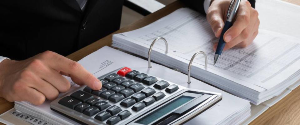 closeup of man's hands doing accounting work on a calculator