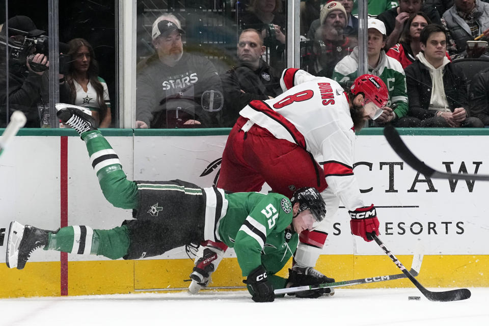 Dallas Stars' Thomas Harley (55) falls to the ice as Carolina Hurricanes' Brent Burns (8) takes control of the puck in the second period of an NHL hockey game in Dallas, Tuesday, Feb. 13, 2024. (AP Photo/Tony Gutierrez)