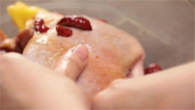 Rubbing marinade into raw duck legs