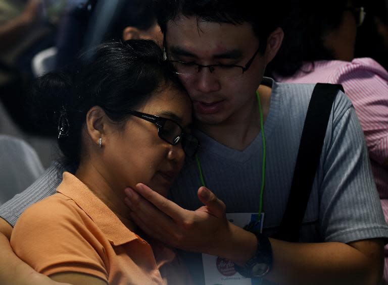 Family members of passengers onboard AirAsia Flight QZ8501 react to news about the discovery of debris found floating in the search area, inside the crisis-centre set up at Juanda International Airport in Surabaya