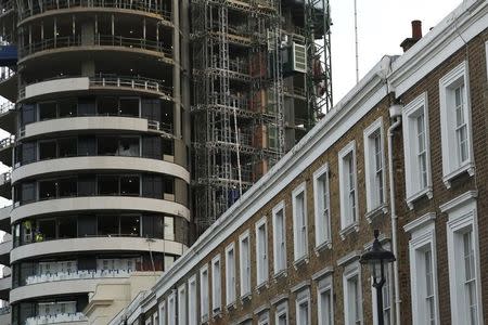 An apartment block is constructed behind a row of traditional properties in central London December 11, 2014. REUTERS/Luke MacGregor