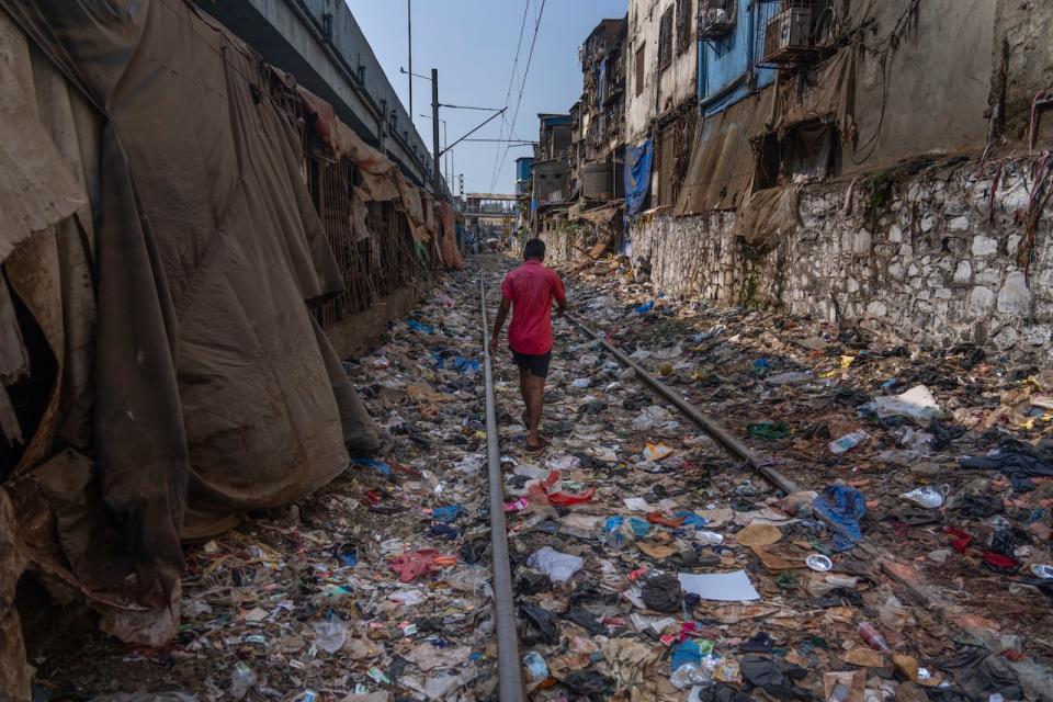 A man walks on a railway track littered with plastic and other waste materials on Earth Day in Mumbai, India on April 22, 2024.