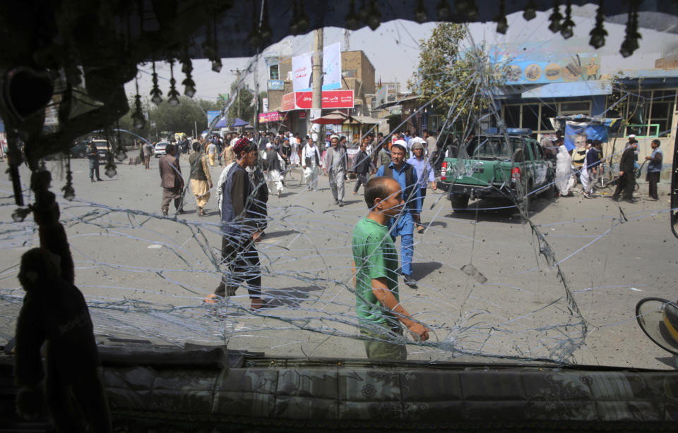 Afghans are seen through a shattered glass of a transport bus broken after an explosion in Kabul, Afghanistan, Wednesday, Aug. 7, 2019. A suicide car bomber targeted the police headquarters in a minority Shiite neighborhood in western Kabul on Wednesday, setting off a huge explosion that wounded dozens of people, Afghan officials said. The Taliban claimed responsibility for the bombing. (AP Photo/Rafiq Maqbool)