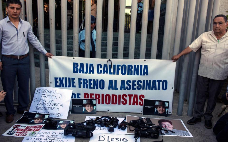 Protesters hold a banner during a demonstration against violence targeting reporters in Tijuana last month - Credit: AFP