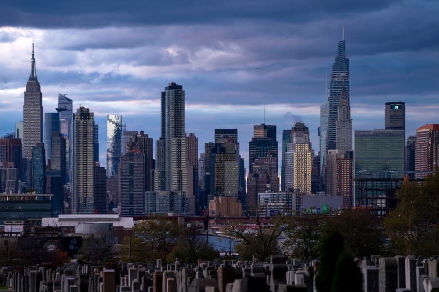 FILE - The sun sets behind the New York skyline, Nov. 13, 2022, as seen from Calvary Cemetery. New York City appears to have gotten an additional 1,090 people added to its population total recently after asking the Census Bureau to double-check the city's numbers from the head count of every U.S. resident, city officials said. (AP Photo/Julia Nikhinson, File)