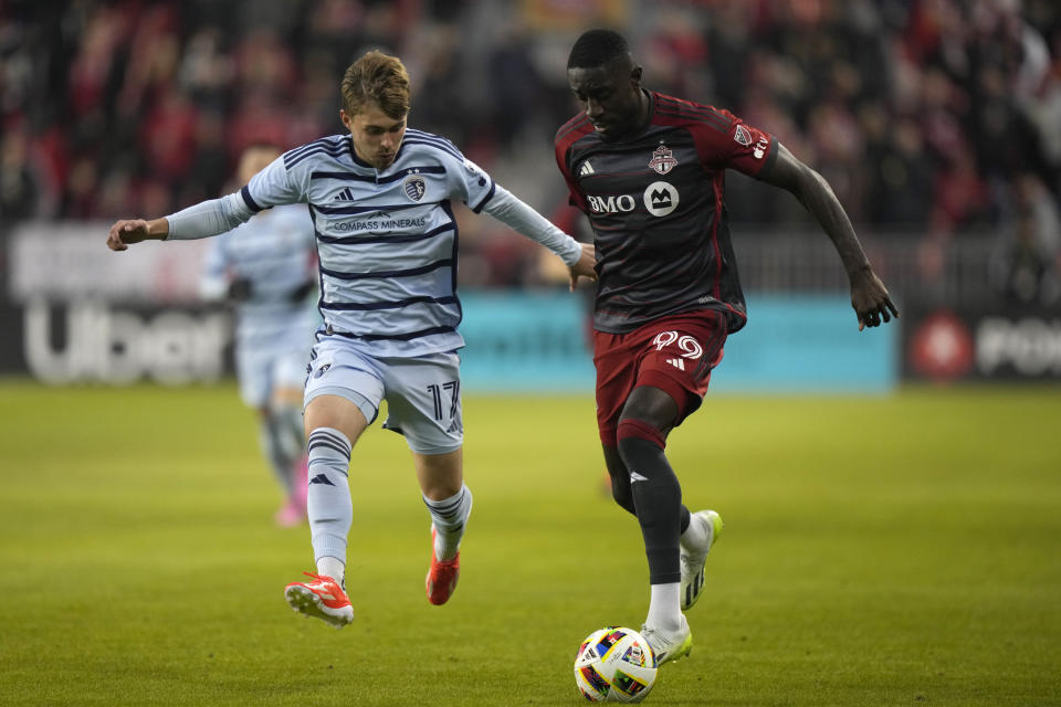 Toronto FC forward Prince Osei Owusu (99) moves the ball upfield as Sporting Kansas City midfielder Jake Davis (17) chases during the first half of an MLS soccer game in Toronto, Ontario, Saturday, March 30, 2024. (Frank Gunn/The Canadian Press via AP)