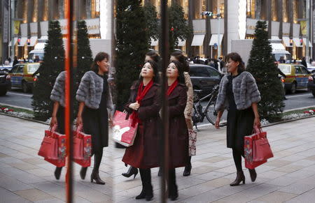 Women are reflected in a window as they pass a boutique in a shopping district in Tokyo, November 26, 2015. REUTERS/Thomas Peter -