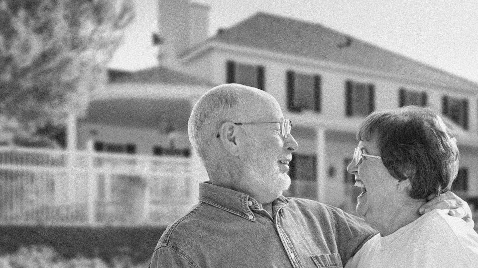 laughing older couple in front of a house