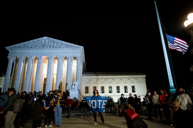 A woman waves a "Vote" sign as people gather outside of the U.S. Supreme Court following the death of U.S. Supreme Court Justice Ruth Bader Ginsburg, in Washington