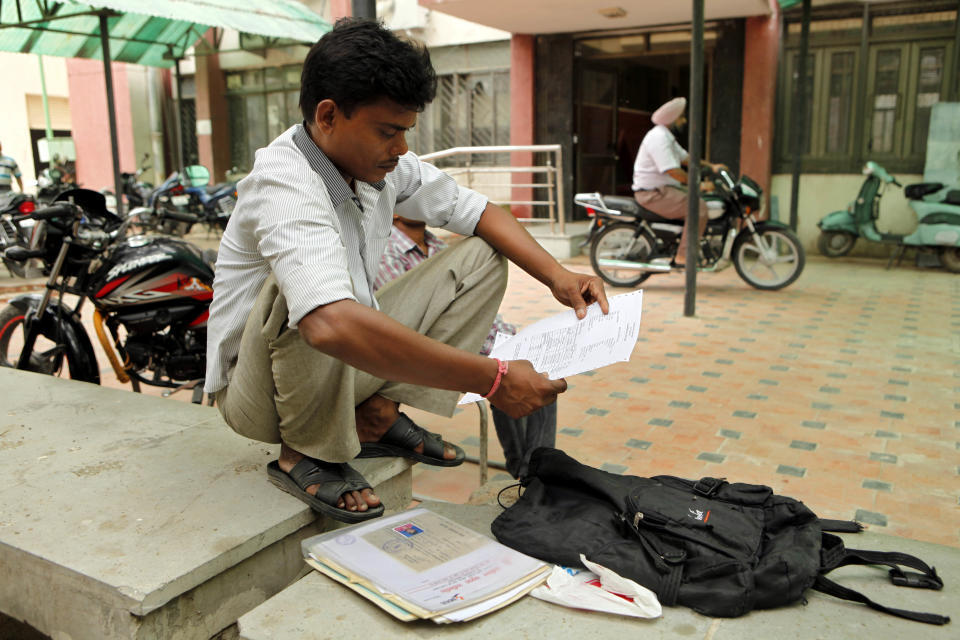 In this photo taken Wednesday, Aug. 29, 2012, an Indian man Vijay Kumar looks at his certificates outside an employment exchange office in New Delhi, India. Thousands of unemployed like Kumar flock to 900 state-run job centers across the country, where they hope to get what many in this country believe is the ticket to a better life, a government job. While millions of job seekers have impressive sounding diplomas, many don't have the skills promised by those certificates from colleges and technical institutes with poor standards. (AP Photo/Rajesh Kumar Singh)