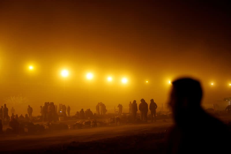 FILE PHOTO: Migrants stand near the border wall during a sandstorm after having crossed the U.S.-Mexico border