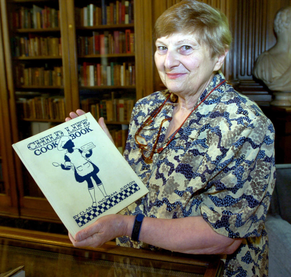 Janice Longone, the culinary curator at the University of Michigan Clements Library, holds one of her favorite cookbooks: "Child Life Cook Book" by Clara Ingram Judson in Ann Arbor, Mich. Longone, who is credited with collecting thousands of items chronicling the culinary history of the United States, including cookbooks, menus, advertisements and diaries, died Wednesday, Aug. 3, 2022, according to Nie Family Funeral Home in Ann Arbor. She was 89. (Larry E. Wright/Ann Arbor News via AP)