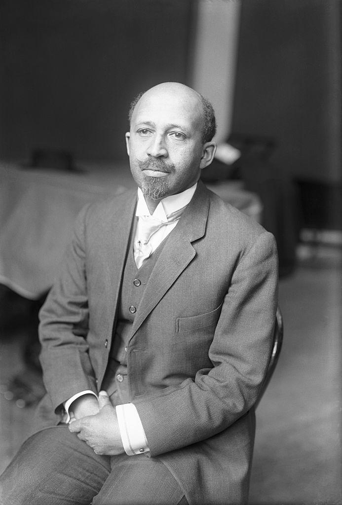 web dubois sits in a chair and wears a three piece suit with a tie