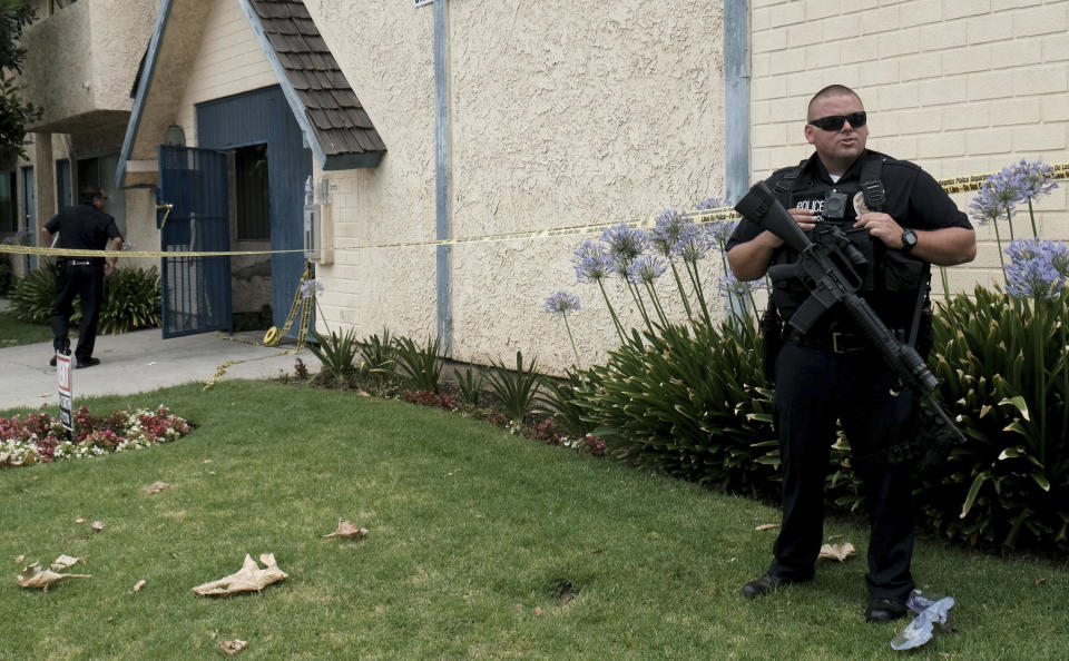 A Los Angeles police officer stands outside of an apartment where a shooting occurred in the Canoga Park area of Los Angeles on Thursday, July 25, 2019. Police say a gunman shot five people, killing three, in two attacks in Los Angeles before he tried to rob someone outside a bank. (Dean Musgrove/The Orange County Register via AP)