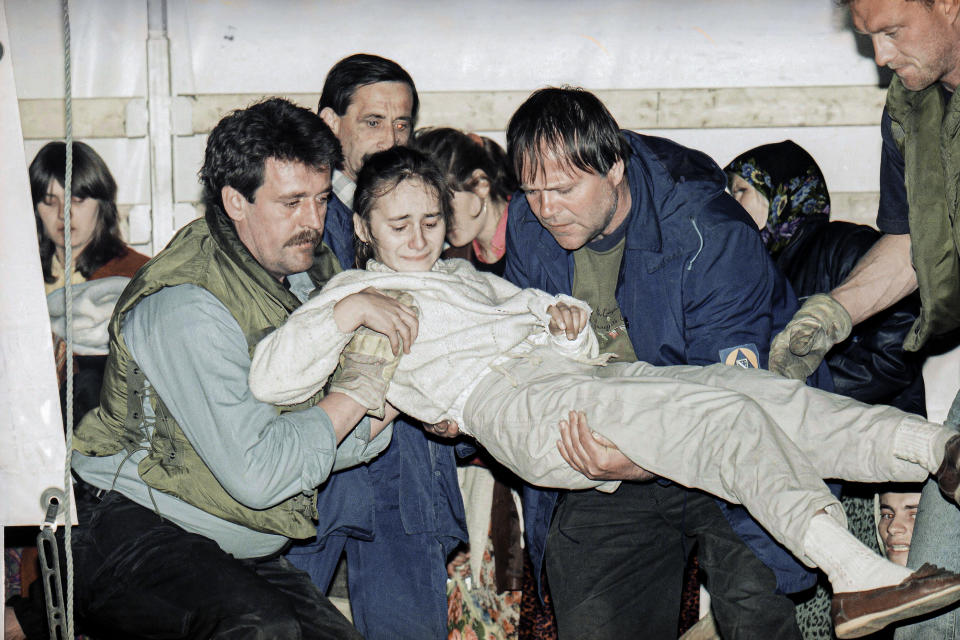 FILE- In this March 20, 1993, file picture, a wounded child form the besieged Bosnian town of Srebrenica is carried off a U.N. truck upon arriving in Tuzla, Bosnia, after a tense journey across the most contested battle lines in Bosnia. Survivors of the genocide in the eastern Bosnian town of Srebrenica, mainly women, will on Saturday July 11, 2020, commemorate the 25th anniversary of the slaughter of their fathers and brothers, husbands and sons. At least 8,000 mostly Muslim men and boys were chased through woods in and around Srebrenica by Serb troops in what is considered the worst carnage of civilians in Europe since World War II. The slaughter was also the only atrocity of the brutal war that has been confirmed an act of genocide. (AP Photo/Michel Euler, File)