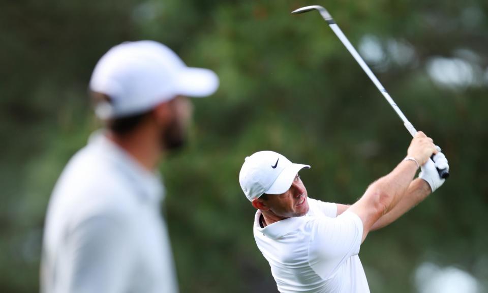 <span>Rory McIlroy plays a shot on the 14th as Scottie Scheffler watches on – McIlroy ended the day one under while Scheffler was five strokes better off.</span><span>Photograph: Andrew Redington/Getty Images</span>