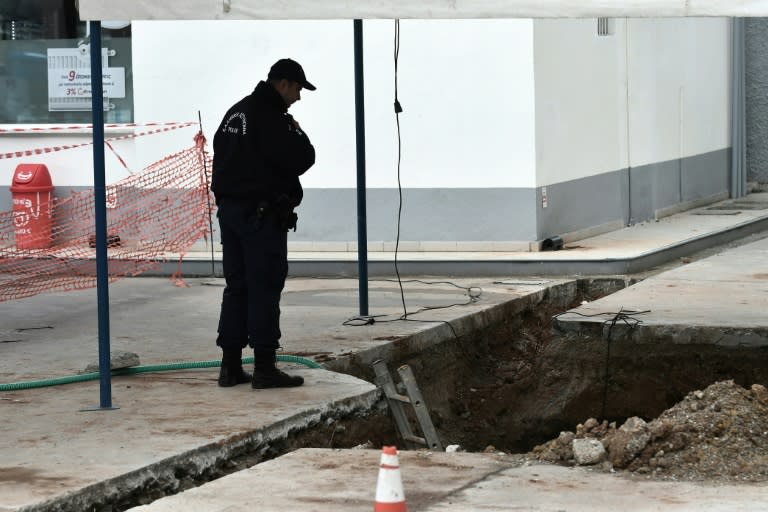 A policeman looks into a hole in Thessaloniki, northern Greece where an unexploded World War II bomb was found during work to expand a petrol station's underground tanks on February 8, 2017