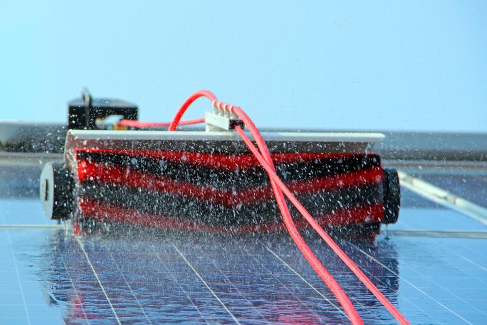 A close up of a brush tool that's being used to clean solar panels. 