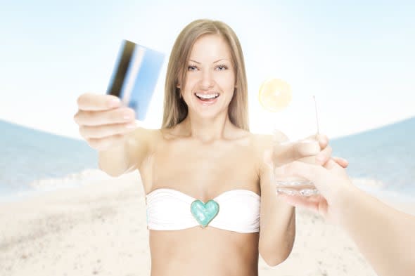 attractive young woman on the beach , paying for a cocktail with credit card