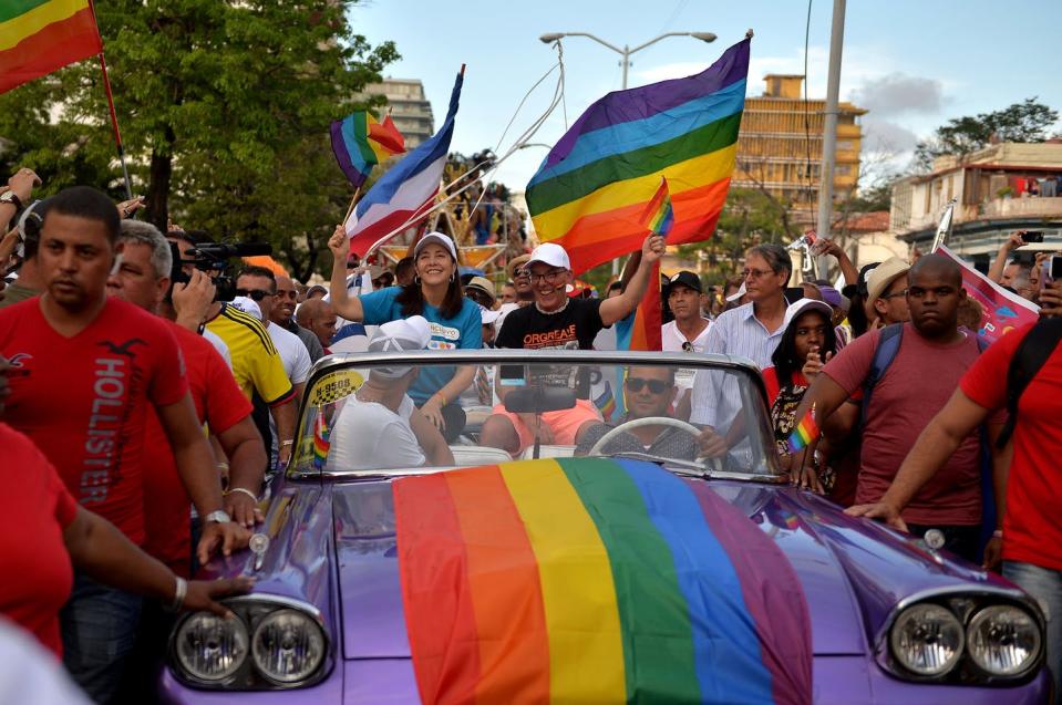 Mariela Castro rides in a car decked out in pride flags surrounded by crowds in a pride parade