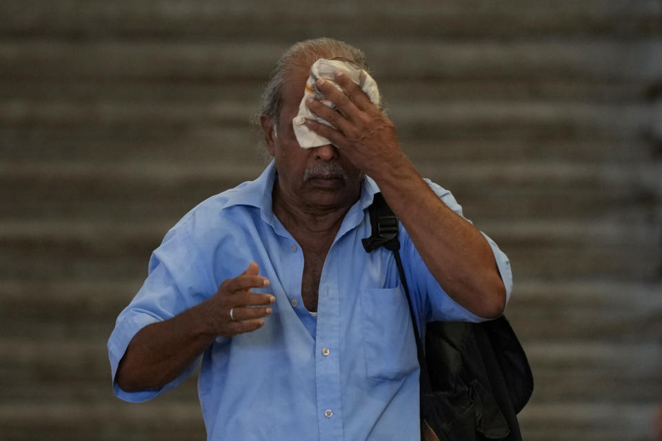 A passenger wipes sweat as he waits for a train during a railway union strike in Colombo, Sri Lanka, Wednesday, July 10, 2024. (AP Photo/Eranga Jayawardena)