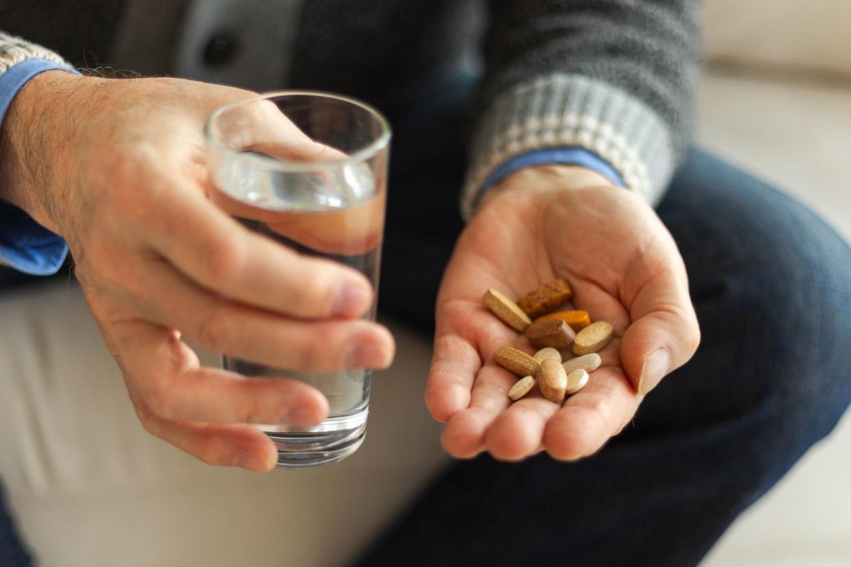 man holding supplement pills