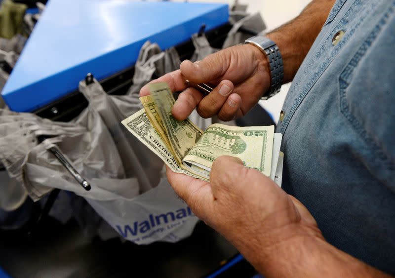 FILE PHOTO: A customer counts his cash at the checkout lane of a Walmart store in the Porter Ranch section of Los Angeles