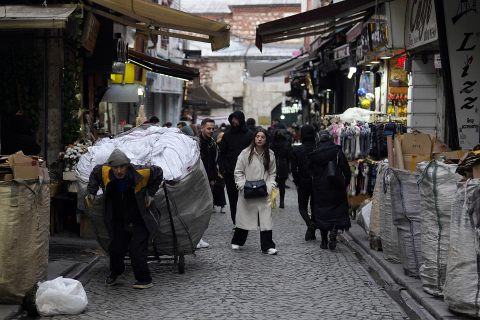 People walk along a street in Beyazit commercial area in Istanbul, Turkey, Wednesday, March 20, 2024. On Sunday, millions of voters in Turkey head to the polls to elect mayors and administrators in local elections which will gauge President Recep Tayyip Erdogan’s popularity as his ruling party tries to win back key cities it lost five years ago. (AP Photo/Khalil Hamra)