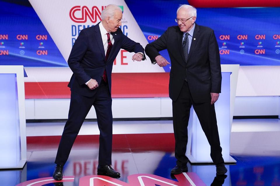 Former Vice President Joe Biden, left, and Sen. Bernie Sanders, I-Vt., right, greet one another before they participate in a Democratic presidential primary debate at CNN Studios in Washington, Sunday, March 15, 2020. (AP Photo/Evan Vucci)