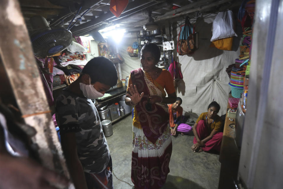 Mina Ramesh Jakhawadiya, center, tells her son Ritik Ramesh, left, not to go out and play because of the coronavirus and be in the house in Mumbai, India, March 30, 2020. Jakhawadiya makes a living selling cheap plastic goods with her husband on the streets of Mumbai. For her, the order means 21 days in a 6-by-9 foot room with five people, no work, a couple days of food and very less cash. (AP Photo/Rafiq Maqbool)