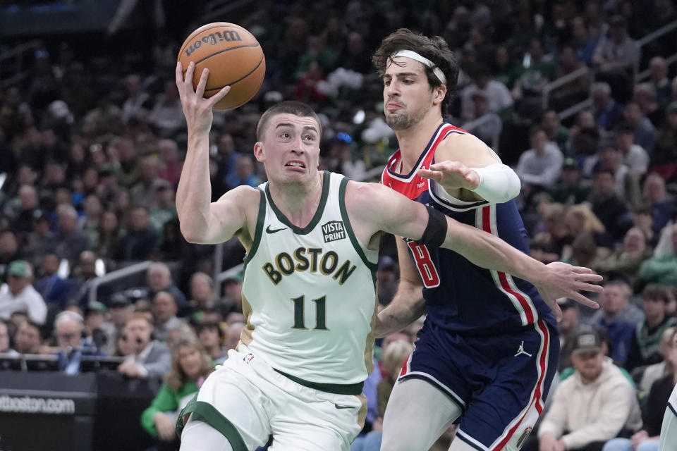 Boston Celtics guard Payton Pritchard (11) drives toward the basket past Washington Wizards forward Deni Avdija (8) in the first half of an NBA basketball game, Sunday, April 14, 2024, in Boston. (AP Photo/Steven Senne)